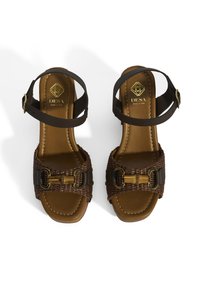 Braune geflochtene Sandalen mit einer Ledersohle, ausgestattet mit einem breiten Riemen mit goldfarbenen Beschlägen und einem schmalen Knöchelriemen. Hergestellt in Italien.