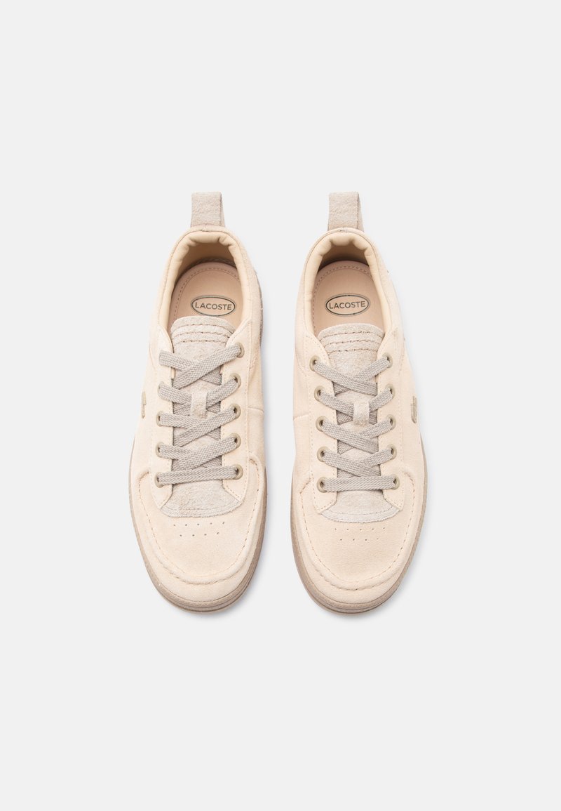 Pair of beige Lacoste sneakers with laces, suede accents, and pull tabs, viewed from above on a light background.