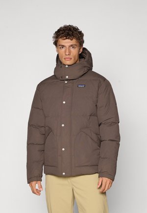Brown insulated puffer jacket with a high collar, snap-button closure, two side pockets, and quilted texture.