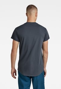 Mörkgrå t-shirt med korta ärmar, rund halsringning och en något rundad nederkant. Mjuk tyg med en slät yta och inga synliga mönster.