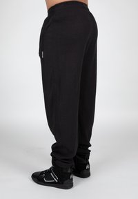 Sorte sweatpants i vaffelmønster har en elastisk talje og smalle manchetter. Designet inkluderer sidelommer og en afslappet pasform.