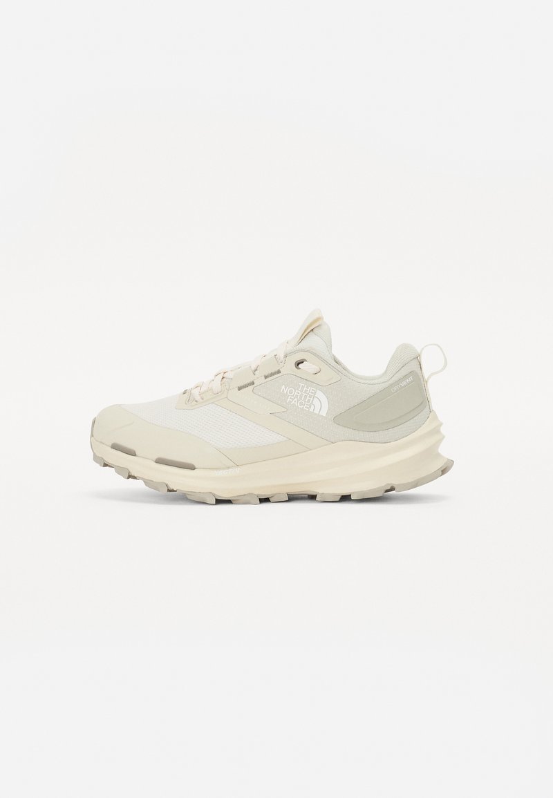 Baskets de course beige clair avec une tige en mesh et en synthétique, bout renforcé et semelle extérieure texturée. Comprend un logo et une languette au niveau du talon.