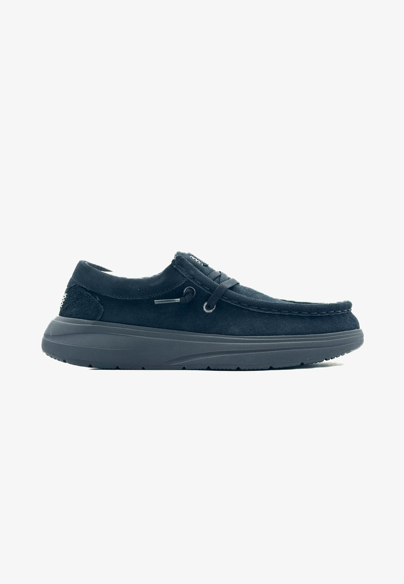 Scarpa nera in suede con design allacciato, dettagli testurizzati, suola in gomma spessa e cuciture lungo i bordi, con punta arrotondata.
