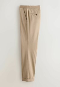 Pantalon beige sur mesure avec poches latérales, poche arrière avec bouton, passants de ceinture et ourlets retroussés, présenté à plat sur un fond clair.