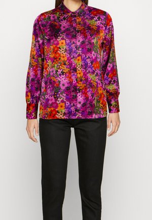 Wielokolorowa kwiecista bluzka z połyskującym wykończeniem, z kołnierzykiem, długimi rękawami oraz mieszanką odcieni fioletu, pomarańczu i zieleni.