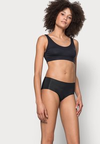 Zwarte naadloze bralette en slipjes set. Glad materiaal, minimalistisch ontwerp, met een ronde halslijn en een mid-rise pasvorm met zachte randen.
