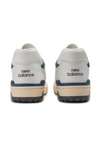 Białe skórzane trampki z ciemnoturkusowymi akcentami, posiadające teksturowaną cholewkę, gumową podeszwę oraz logo „new balance” wyszyte na pięcie.