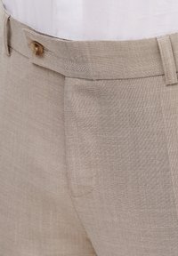 Beżowe spodnie lniane o teksturowanej tkaninie, z pojedynczym zapięciem na guzik i boczną kieszenią. Dopasowany krój z czystym wzornictwem.