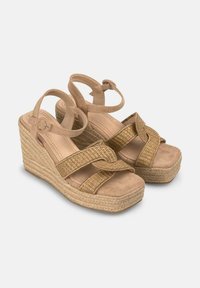 Beige wedge sandalen met een gevlochten jute hiel, voorzien van kruislings met zachte suède gemaakte bandjes en verstelbare enkelbandjes.