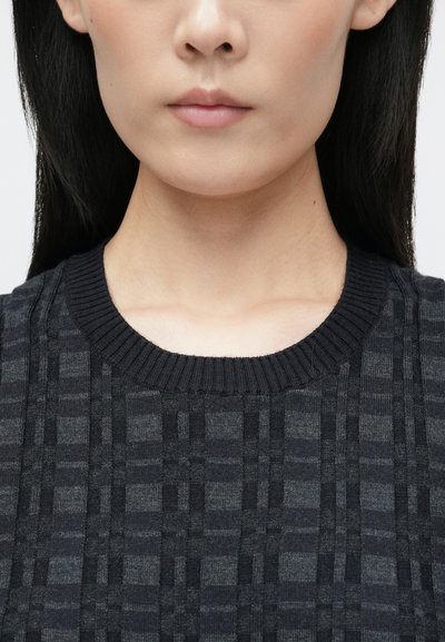 Pullover întunecat din tricot, cu un model texturat de carouri, guler rotund cu elastic și material moale. În principal negru, cu nuanțe subtile de gri.