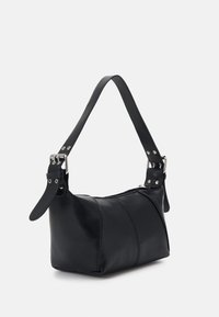 Sac à main en cuir noir avec bandoulière réglable à boucle et fermeture éclair supérieure, présenté sur un fond clair.