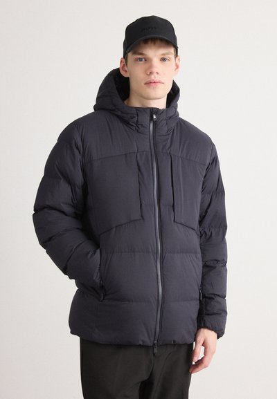 Doudoune marine avec capuche, dotée d'une fermeture éclair sur le devant, de deux poches sur la poitrine et d'un design matelassé. Fabriquée en tissu doux et léger.