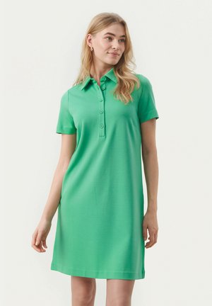 Grünes Polo-Kleid aus leichtem Material. Kurze Ärmel, Kragen mit Knöpfen und lockere Passform. Glatte Textur ohne Muster.