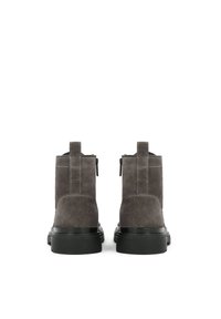 Botas tobilleras de ante gris con superficie lisa, suelas de goma negra y cremallera lateral. Incluyen una lengüeta en la parte trasera para facilitar su uso.