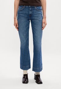 Denim flare jeans v svetlo modrem materialu, z visokim pasom, petimi žepi in kontrastnim šivom, končane z zavihanjem robov.