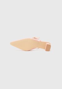 Pink pointed-toe shoe with a woven textured upper and a small square heel. The sole is light tan with subtle grooves for grip.