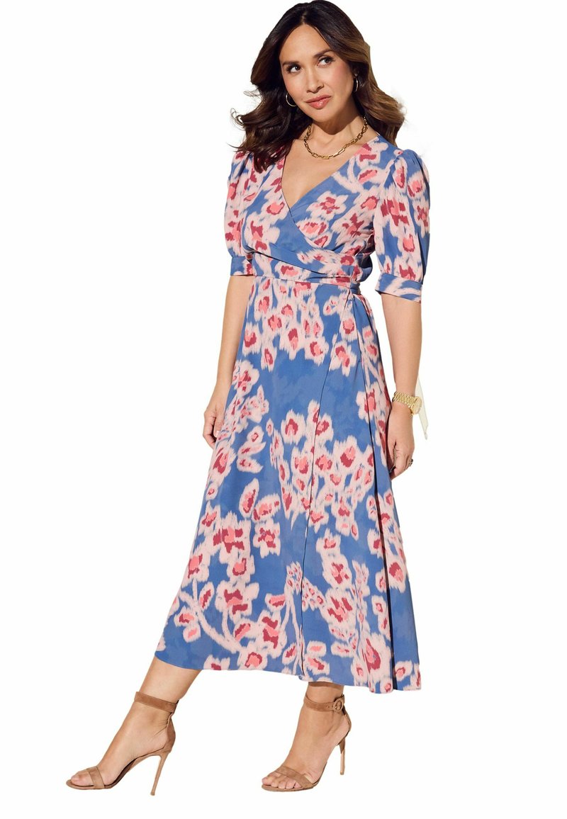Floral-Print Wickelkleid in Blau und Pink mit kurzen Puffärmeln, einem taillierten Gürtel und einem schwingenden Rock. Kombiniert mit nudefarbenen Strappy-Heels.