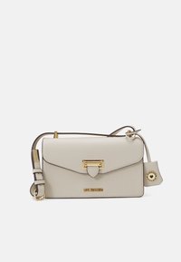 Borsa a tracolla in pelle beige con chiusura in oro, dettagli con zip e tracolla regolabile. Presenta un logo e un piccolo tag decorativo.