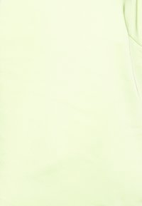 Camisa de manga curta verde-claro, com textura suave, decote arredondado, possui um bolso no lado esquerdo do peito. Design simples e sólido, sem padrões ou detalhes.