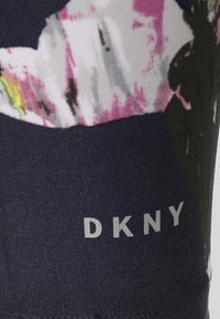 Legíny DKNY s tmavě námořnickým základem, který je pokrytý mnohobarevným květinovým vzorem a stříbrným logem na levé dolní nohavici.