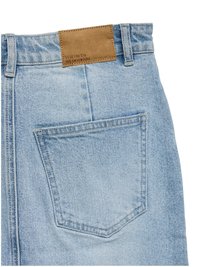 Svetlomodré riflové nohavice zobrazujú zadný vrecko a hnedú koženú značkovú nášivku s textom "VERO MODA WE DO DENIM".