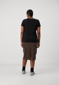 Juodas medvilnės marškinėlis trumpomis rankovėmis. Rudas sijonas su dviem šoninėmis kišenėmis ir nugaros skaidrė. Pilkos sportinės bateliai ir juodos kojinės. Balta fono.