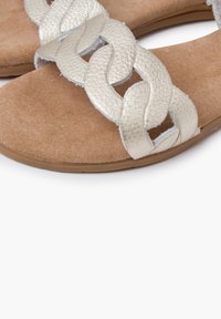 Silver braided strap sandals with a textured upper, soft brown suede footbed, and flat rubber sole. Features an open design for breathability.