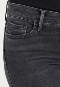 Mörkgrå denimjeans med en figurnära design. Har en liten myntficka, synlig sömnad och en slät yta. Ingen slitning.