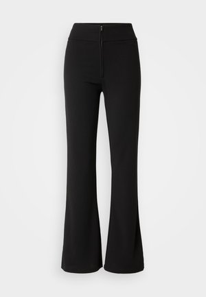 Black flared pants made from stretchy fabric, featuring a fitted high waist and a front zip detail. Smooth texture with no patterns.