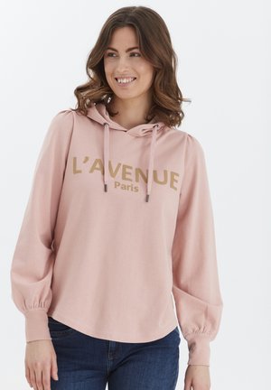 Vaaleanpunainen huppari, jossa on naru, ylisuuret hihat ja rohkea kultateksti, joka lukee "L'AVENUE Paris" edellä.
