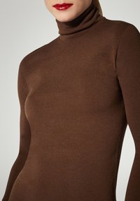 Maglione dolcevita marrone realizzato in morbido tessuto lavorato a maglia elasticizzato. Presenta una silhouette aderente e maniche lunghe, con una texture liscia.