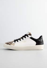 Sneakers con una parte anteriore con motivo a serpente, lati neri con texture, retro bianco e accenti beige. Suola in gomma, lacci neri e dettagli del logo.