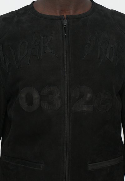Jachetă din suede negru, cu impresii "WORK" și "032C" pe partea din față, design structurat cu guler înalt și fermoar.