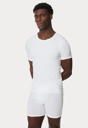 T-shirt blanche ajustée et boxers, fabriqués en matériau doux, affichant un design simple avec des manches courtes et un col rond.