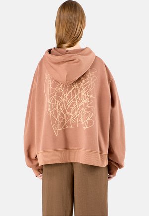 Oversized hooded sweatshirt in muted rose, featuring cream abstract line design on the back, textured fabric, and ribbed hem.