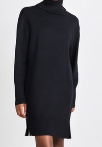 Schwarzes Strickkleid mit hohem Rollkragen, langen Ärmeln und gerippten Bündchen. Verfügt über seitliche Schlitze am Saum für zusätzlichen Schwung.