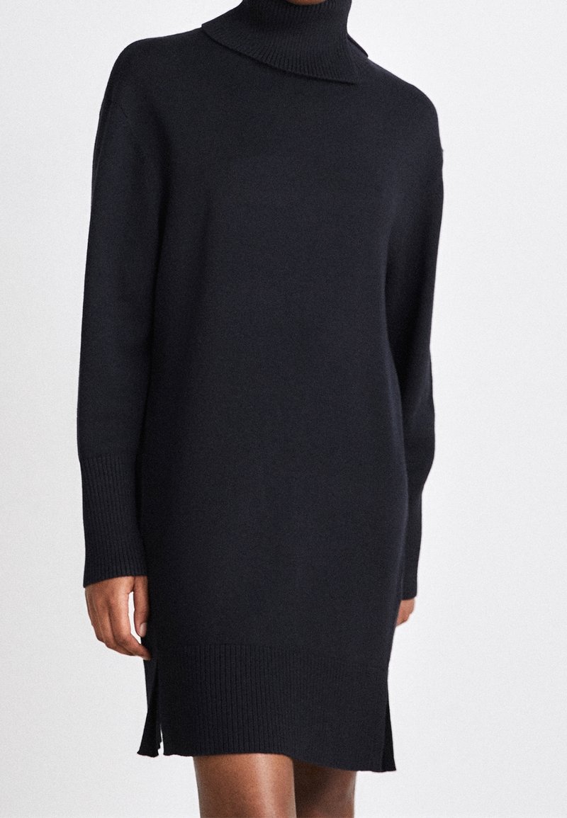 Schwarzes Strickkleid mit hohem Rollkragen, langen Ärmeln und gerippten Bündchen. Verfügt über seitliche Schlitze am Saum für zusätzlichen Schwung.