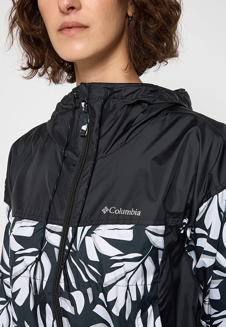 Chaqueta con capucha en negro con un patrón de hojas blancas, que cuenta con un cierre de cremallera en la parte delantera, material liviano y el logo de Columbia en el pecho.