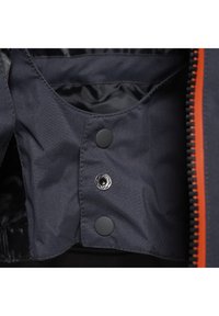 Marinefarget interiør av en jakke med glatt stoff og svarte trykknapper. En oransje glidelås-kant er synlig på høyre side.