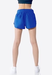 Pantaloni sportivi blu con vita elastica, tasche laterali e vestibilità ampia. Il materiale è liscio e leggero.