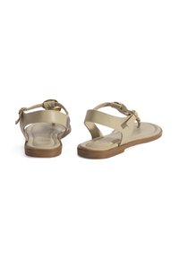 Beige sandalen met een platte zool, voorzien van een driehoekige teenpost en een verstelbare enkelband. Gemaakt van glad leer met minimale details.