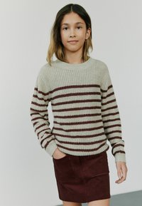 Pull en maille gris clair avec des rayures horizontales bordeaux, col rond et manches longues. Assorti à une jupe en velours côtelé bourgogne.