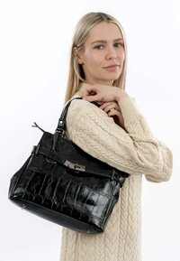 Svart handväska i konstläder med krokodilstruktur, silverfärgad hårdvara och avtagbar axelrem. Har ett handtag upptill och magnetisk stängning.