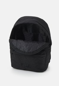 Zaino in tessuto nero trapuntato con chiusura a zip. Presenta un ampio interno foderato e un design testurizzato, con il logo Fila.