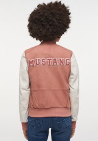 Skórzana kurtka bombowa, różowe body, białe rękawy. Na plecach haftowane "MUSTANG" w kontrastującym czerwonym kolorze. Żebrowany kołnierz i mankiety.