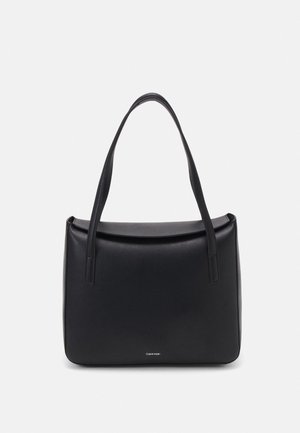 Black leather shoulder bag with long straps, rectangular shape, flap closure, and small Calvin Klein logo at the bottom center.