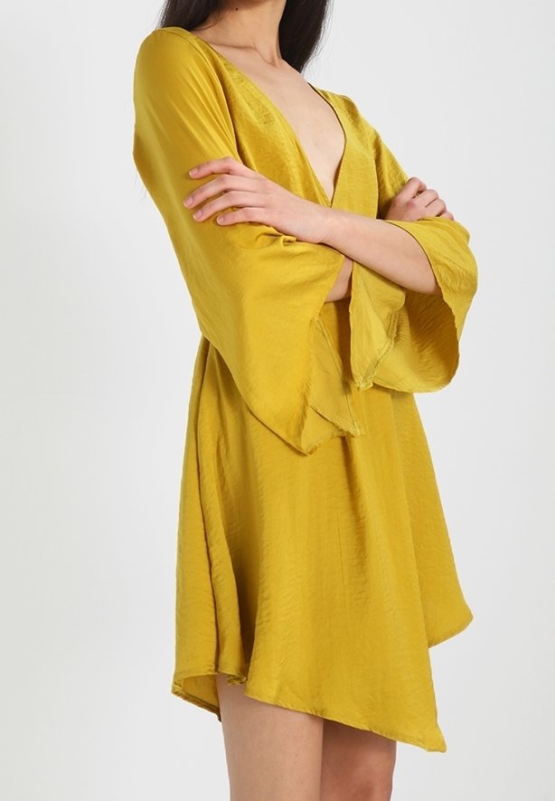 Robe légère jaune avec un décolleté en V profond et des manches amples. Dotée d'une coupe décontractée et d'un ourlet asymétrique. Texture lisse.