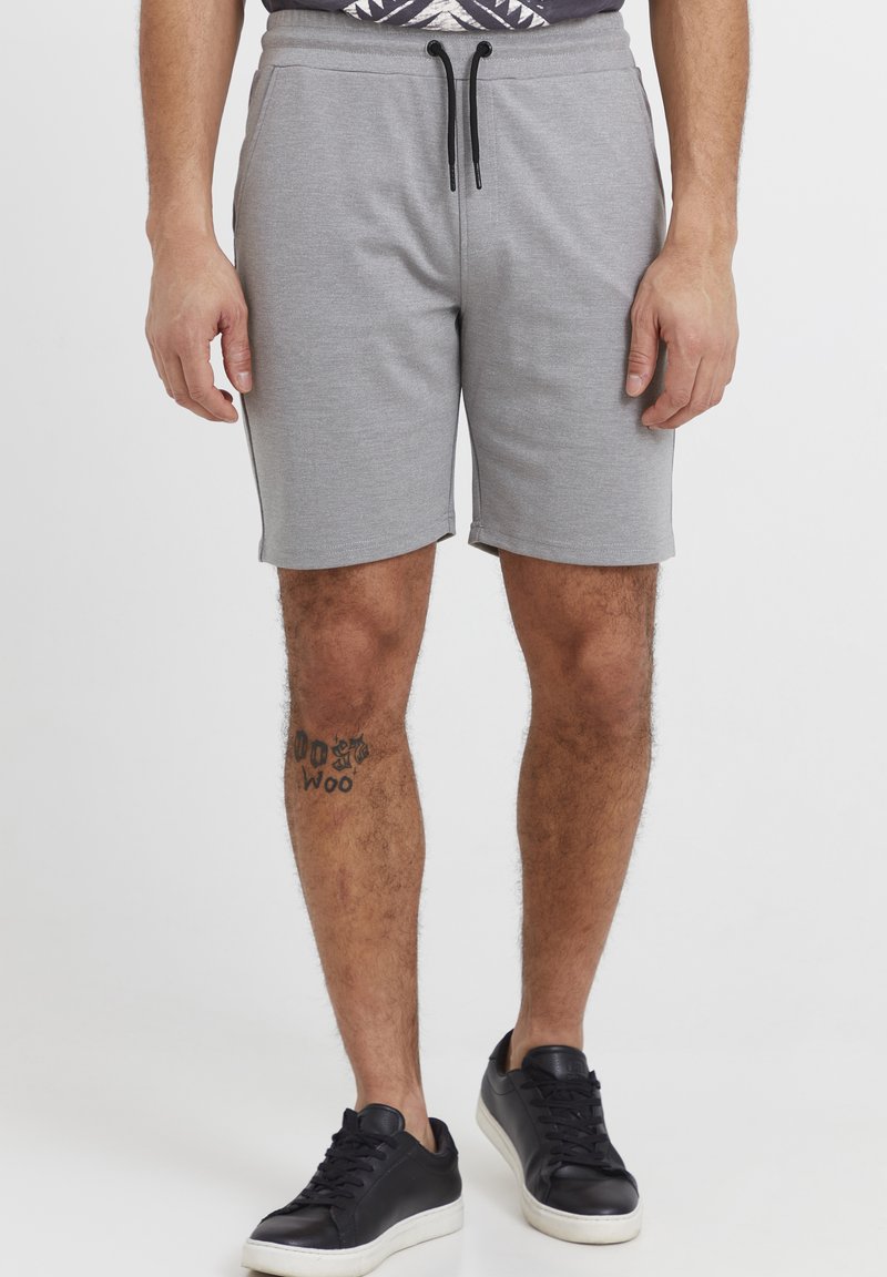 Grå bomullsshorts med elastisk midje og svart snor. Har sidelommer, en glatt tekstur og en tett passform.