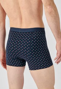 Boxer in blu navy con un motivo geometrico di piccoli triangoli rossi e bianchi. Tessuto morbido e cintura solida.