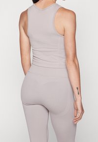 Athletisk linne och leggings i ljus taupe, tillverkade av elastiskt tyg; har en figurnära design och slät textur; minimal sömnadsdetaljer.